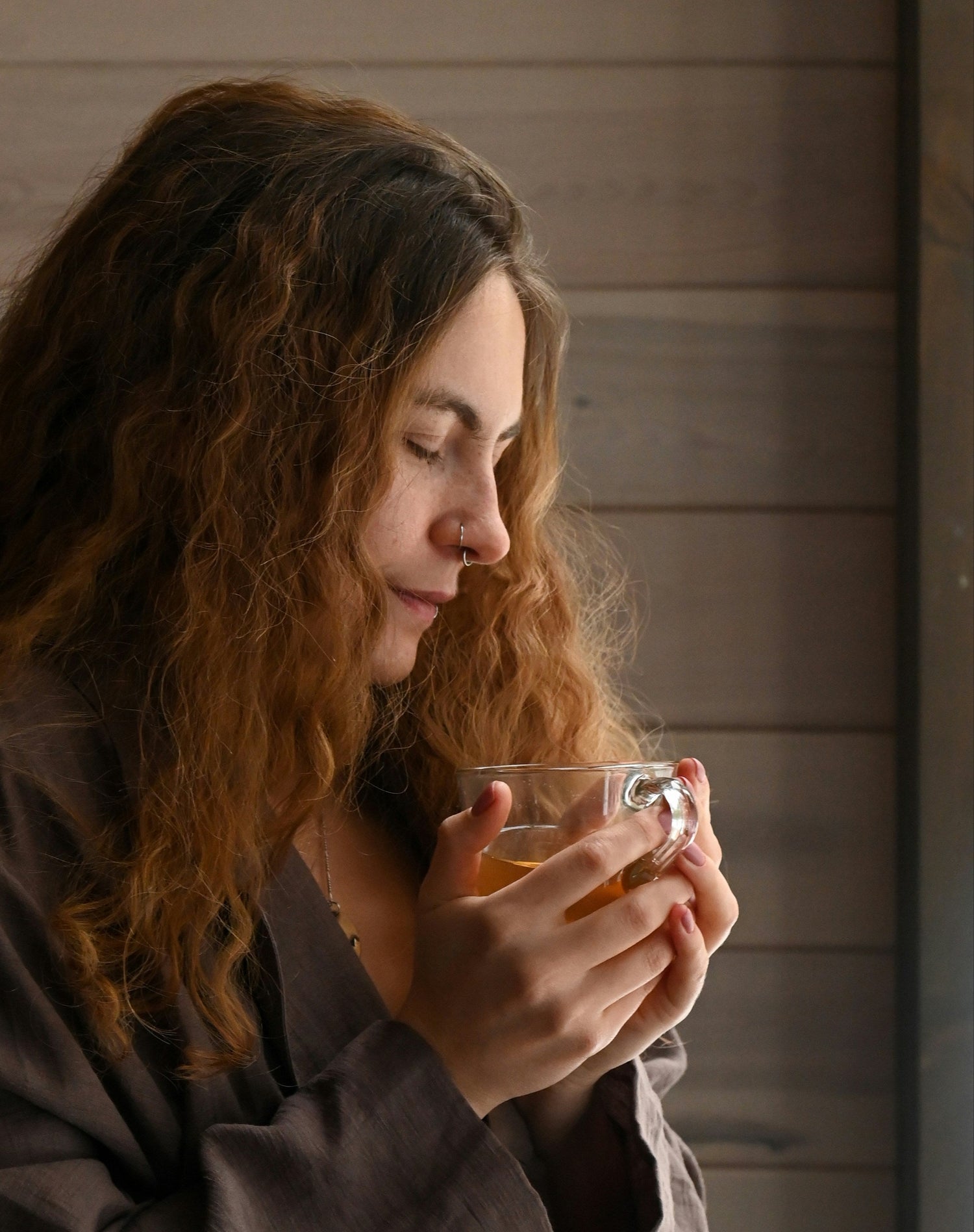 Hand holding a mug of BioBru mushroom coffee with forest mushrooms in background and tagline: Nourish Your Biome, Cultivate Balance, Empower the Spectrum